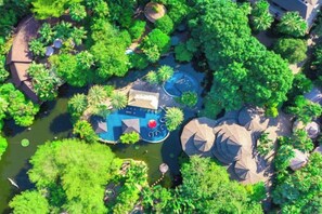 An aerial view of a resort with a swimming pool surrounded by lush greenery and rock formations. - Riyuegu Hot Springs Hotel (Xiamen)