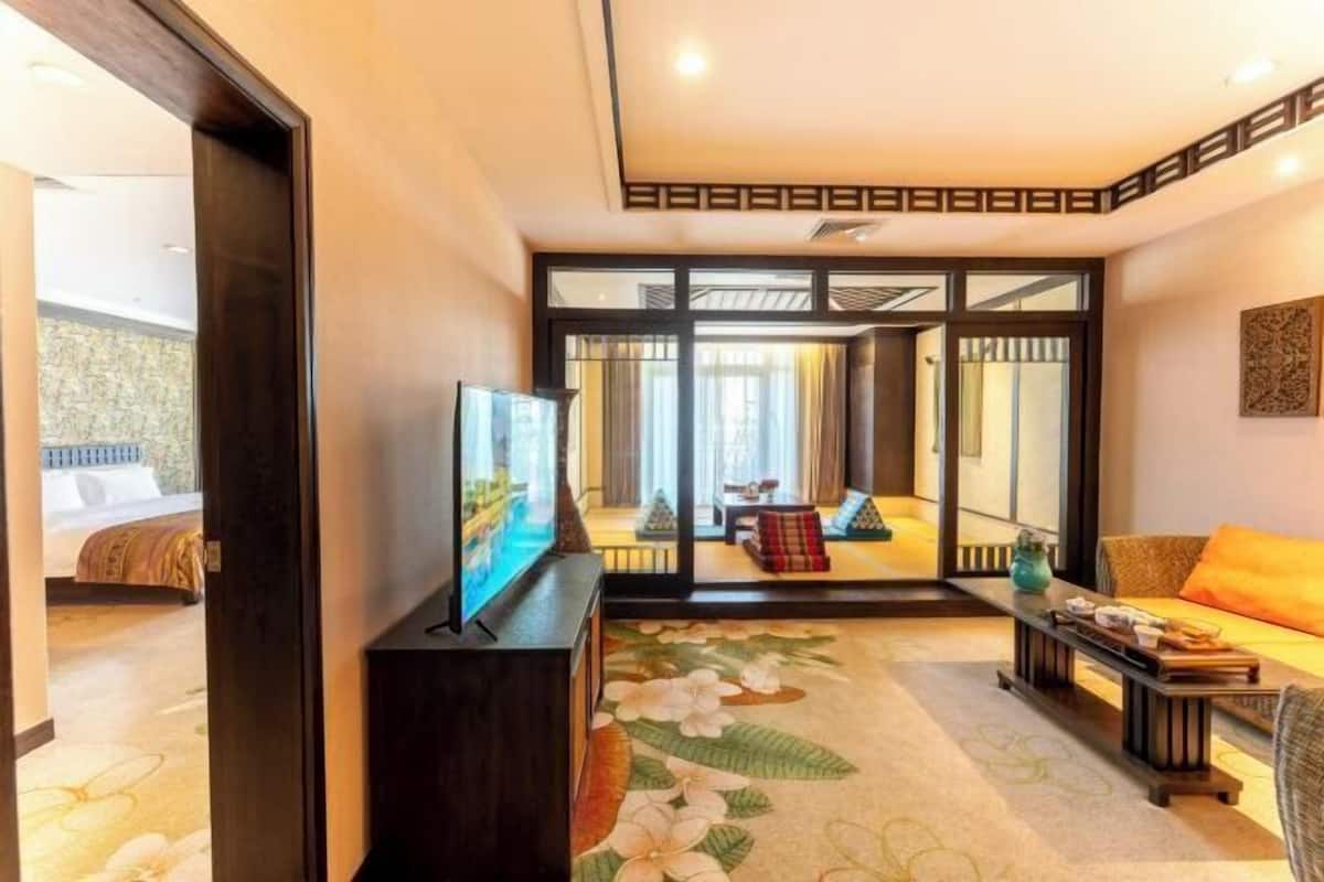 A hotel room with a bed, a TV, a sofa, a coffee table, and a large mirror.