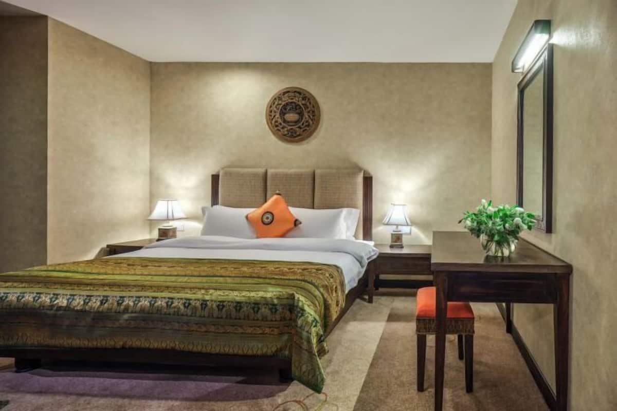 A hotel room with a bed, bedside tables, a desk, and a chair.