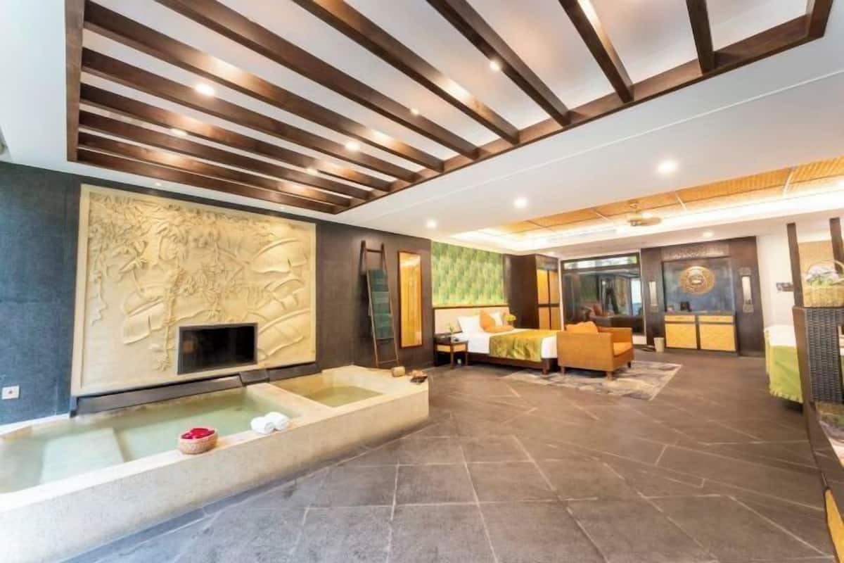 A modern hotel lobby with a large stone bathtub, a reception desk, and a seating area with a sofa.