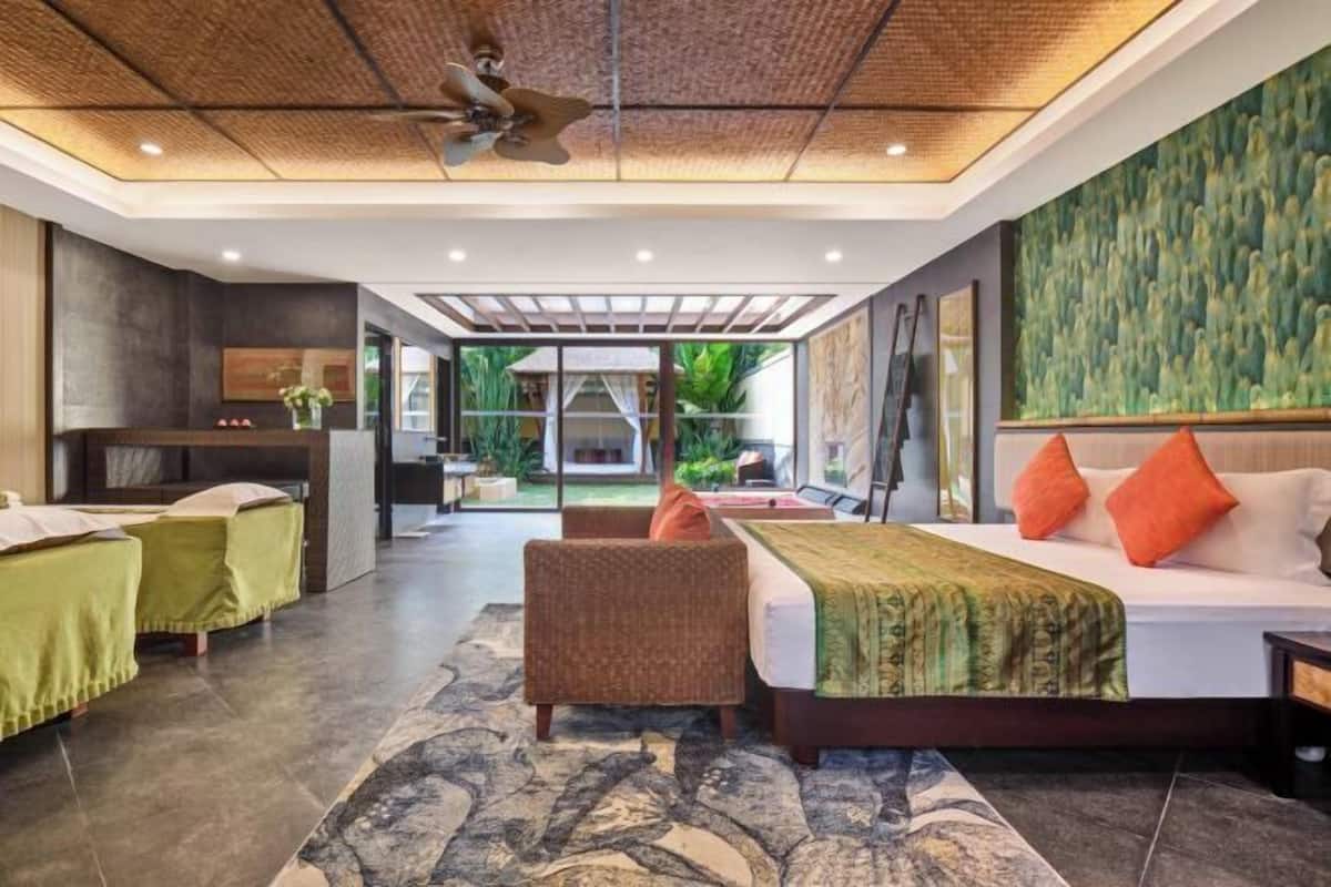 A modern hotel room with a bed, seating area, and a view of the outdoors.