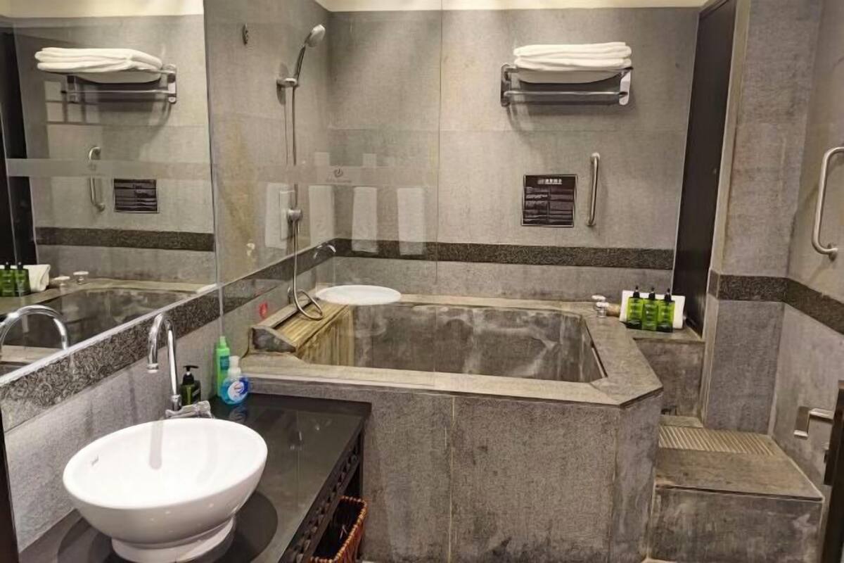 A bathroom with a large bathtub, a sink, and a mirror.
