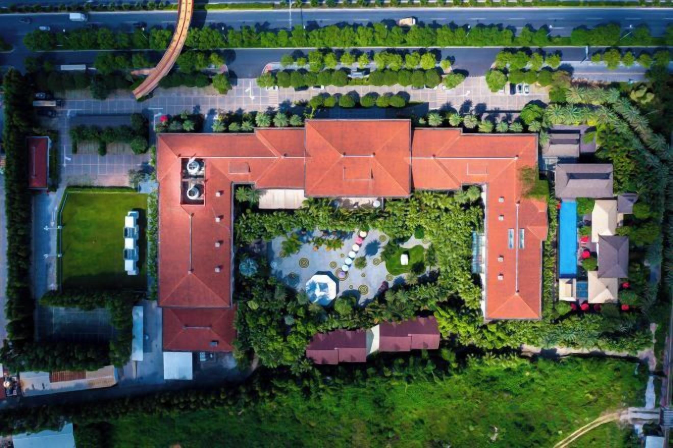 Luchtbeeld van een gebouwcomplex met meerdere gebouwen, een centrale binnenplaats en omliggend groen.