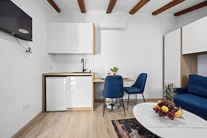 Ein kompakter Wohnraum mit Küchenzeile, Essbereich und einer Sitzecke mit Sofa und Sesseln.