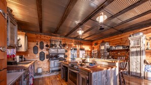 A rustic cabin kitchen with wooden walls, a central island, and a metal ceiling. - Rocky Mt Lodge - Hot tub, Firepit, Fishing, Floating, Large Mountian Getaway (Elkins)