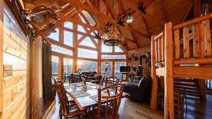 A rustic cabin interior with a wooden dining table, chairs, a fireplace, and a cozy seating area. - Rocky Mt Lodge - Hot tub, Firepit, Fishing, Floating, Large Mountian Getaway (Elkins)