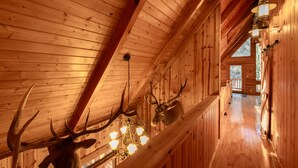 A wooden interior with a high ceiling, a chandelier, and mounted deer heads. - Rocky Mt Lodge - Hot tub, Firepit, Fishing, Floating, Large Mountian Getaway (Elkins)