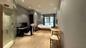 A modern hotel room with a bed, a desk, a chair, and a small table. - Crossing E-sports Hotel (Wenzhou)
