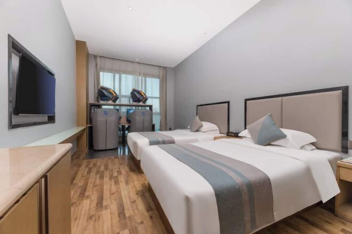 Una habitación de hotel con dos camas, un escritorio y un televisor.
