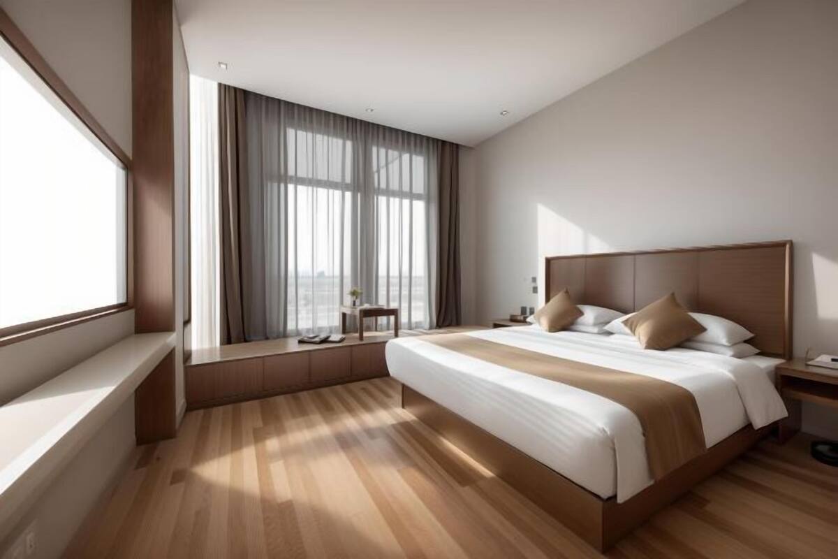 Una habitación de hotel moderna con una cama grande, una ventana con cortinas, una mesita de noche y vistas a la ciudad.