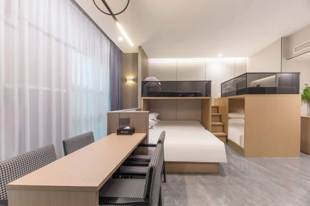 Habitación de hotel pequeña con una cama litera, un escritorio y una zona de comedor.