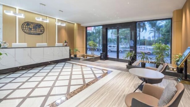 A modern lobby with a reception desk, seating area, and large windows offering a view of the street. - Crossing E-sports Hotel (Wenzhou)