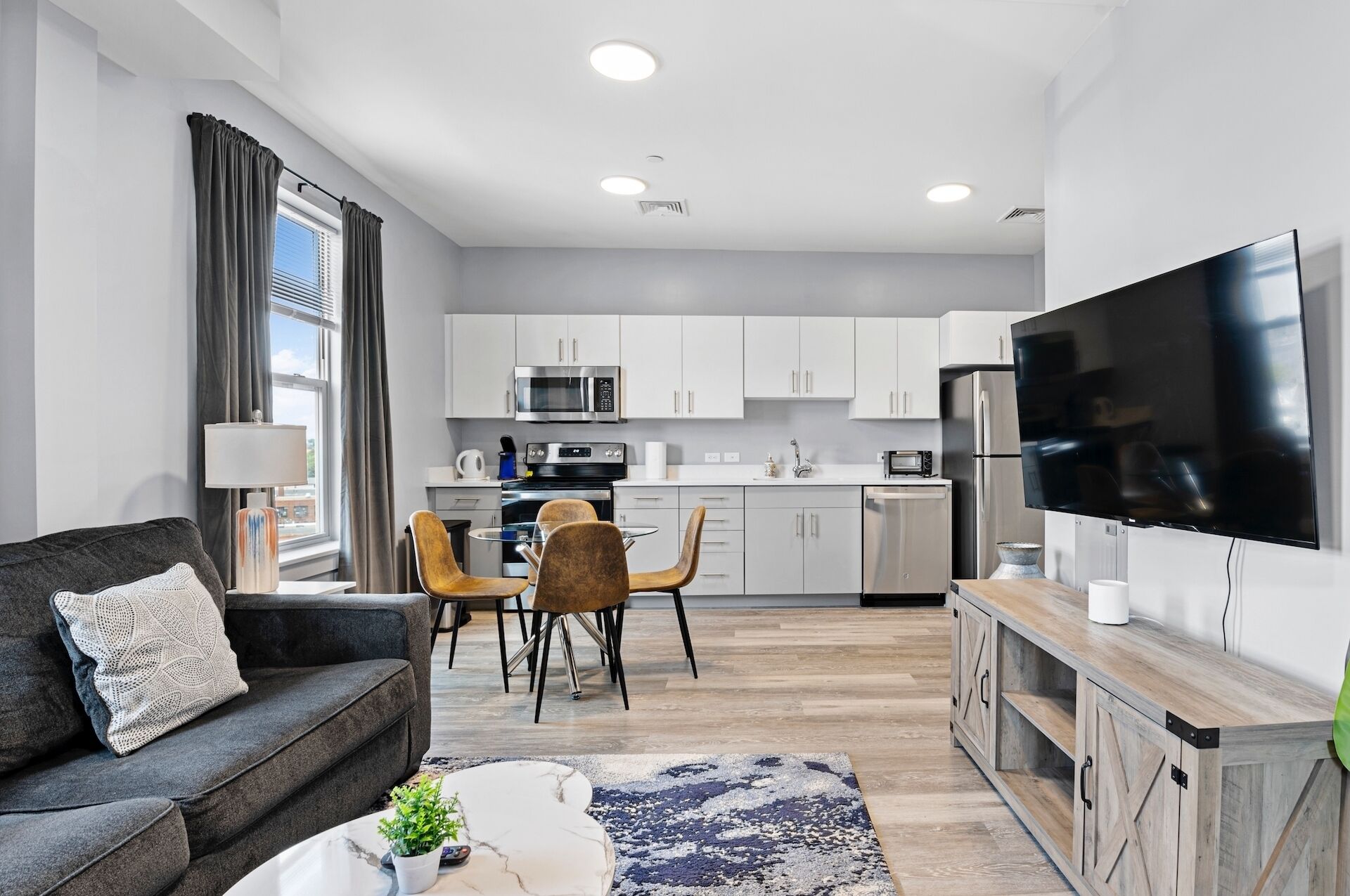 A modern apartment with a living room, dining area, and kitchen.