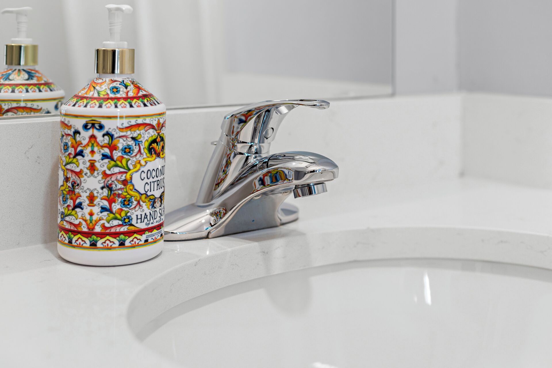 A bathroom sink with a chrome faucet and a colorful hand soap dispenser.