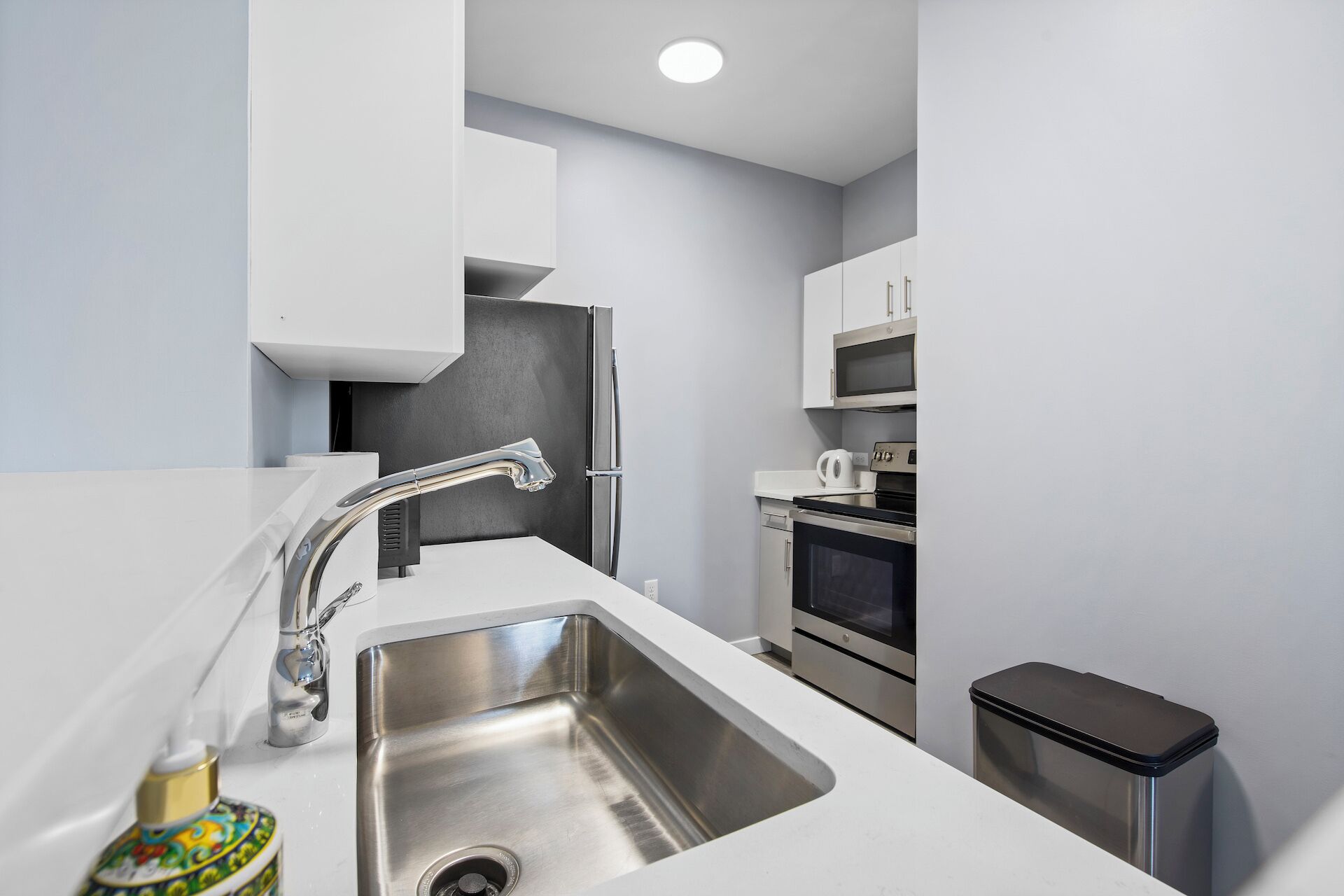 A modern kitchen with a stainless steel sink, a microwave, and an oven.
