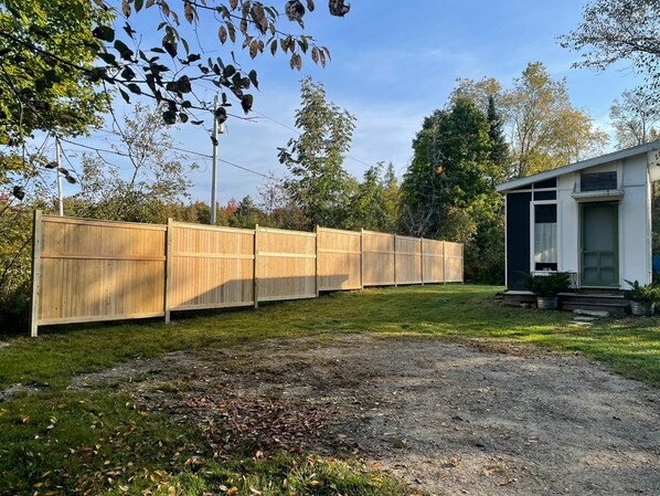 A fenced backyard with a gravel path leading to a house.