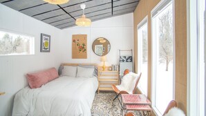 A bedroom with a bed, a chair, a table, a mirror, and a window. - Glamping hut with WiFi in Ripton, biking, hiking, skiing (Ripton)
