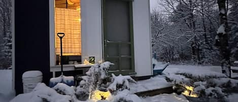 A snow-covered house with a lit entrance and a small outdoor light feature.