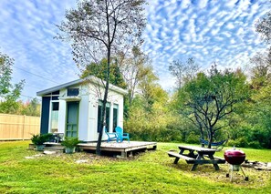 A small house with a deck, a picnic table, and a barbecue grill in a backyard. - Glamping hut with WiFi in Ripton, biking, hiking, skiing (Ripton)