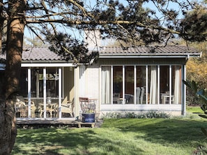 Una casa con un portico, un'area pranzo con sedie e un'ampia finestra.