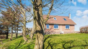 A single-story brick house with a sloped roof, a small attached garage, and a grassy yard. - 5 Person Holiday Home in Snedsted (Snedsted)