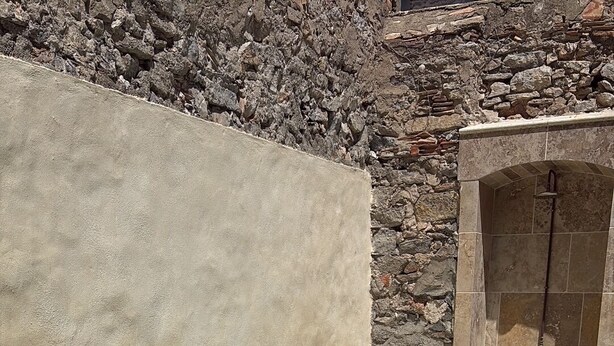 Een zwembad met helder water, omringd door stenen muren en een betonnen constructie.