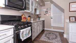A kitchen with white cabinets, a black stove, a microwave, and a large window. - Historic 4-bedroom house one block from Saratoga Racetrack (Saratoga Springs)