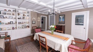 A dining area with a table set for four, surrounded by wooden chairs and a patterned rug. - Historic 4-bedroom house one block from Saratoga Racetrack (Saratoga Springs)