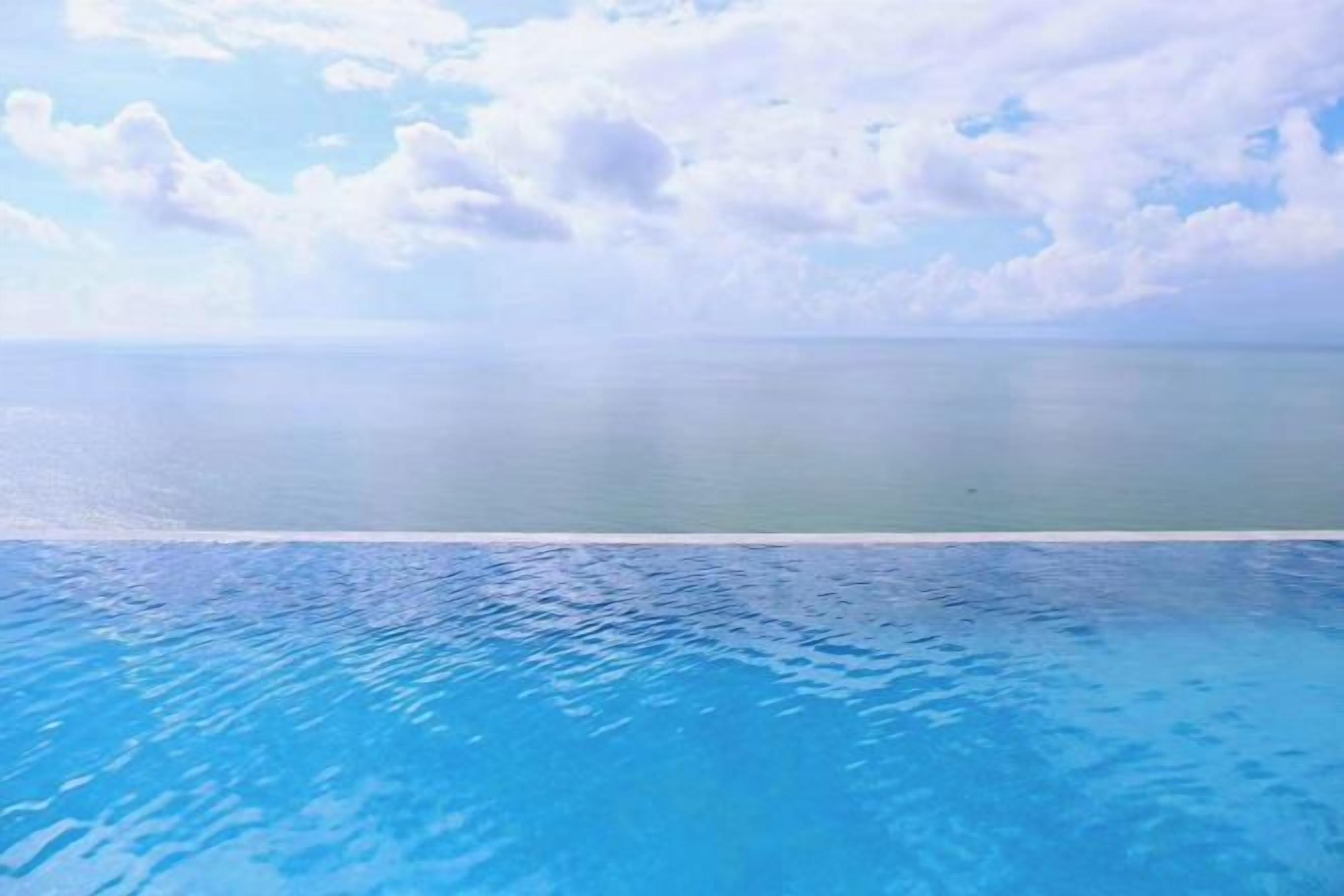 A clear view of a swimming pool with a horizon line and a calm sea in the background.