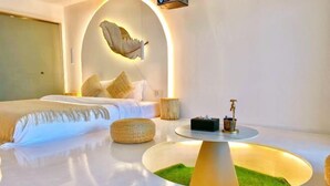 Une chambre moderne avec un lit, une table basse ronde et un arc décoratif original sur le mur.