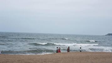 Een strand met golven, een zandstrand en een landmassa in de verte.