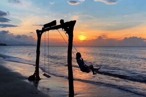 A swing set on a beach with the ocean and sunset in the background. - Huidong Shuangyue Bay Rainbow Bay Sea View Hotel (Huidong)