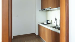 A small kitchen with wooden cabinets, a stainless steel sink, and a kettle on the countertop. - Huidong Shuangyue Bay Rainbow Bay Sea View Hotel (Huidong)
