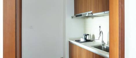 A small kitchen with wooden cabinets, a stainless steel sink, and a kettle on the countertop.