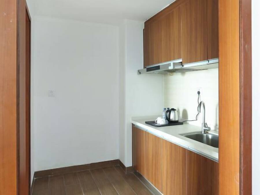 A small kitchen with wooden cabinets, a stainless steel sink, and a kettle on the countertop.