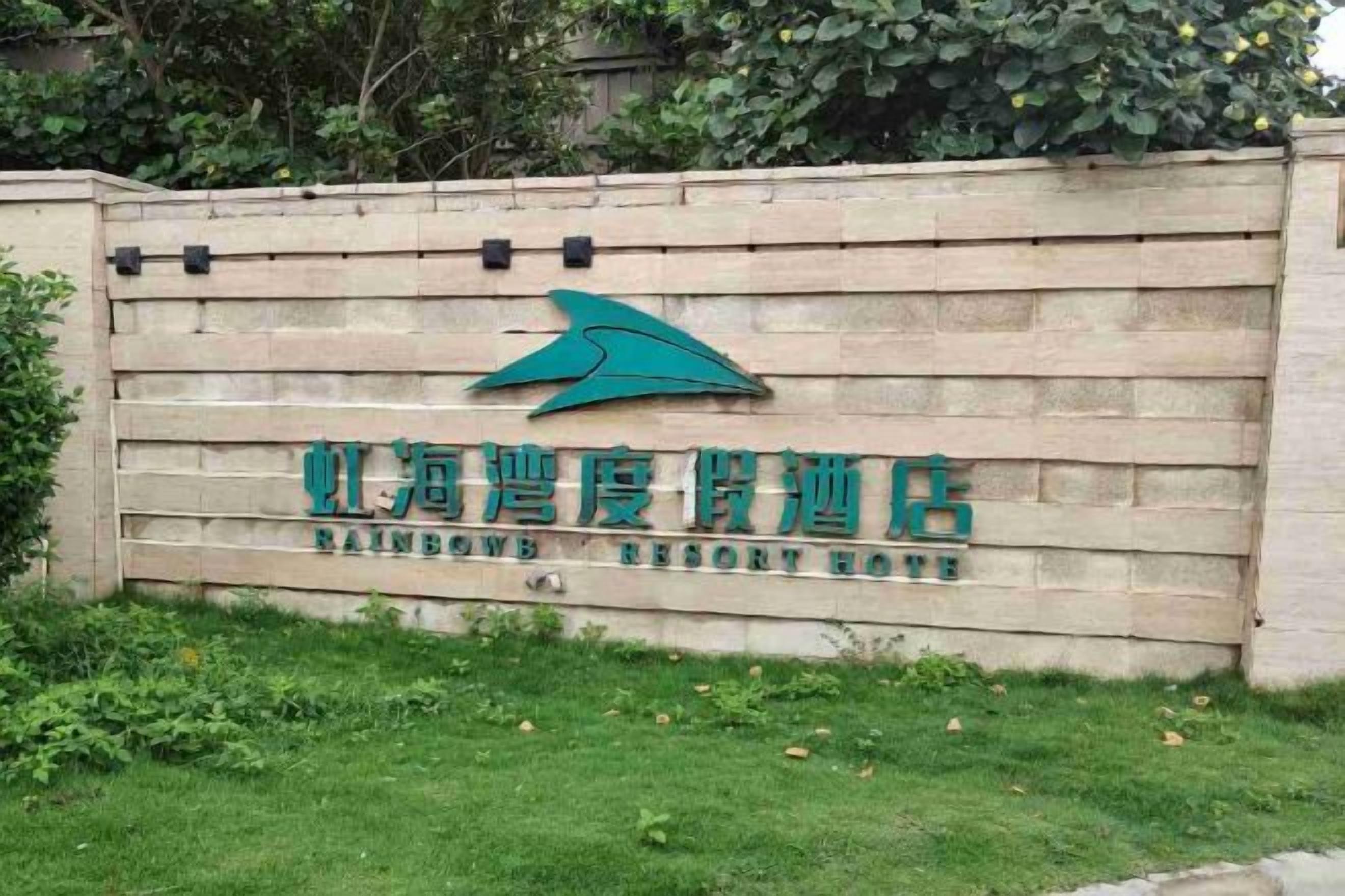 Een bord voor Rainbow Resort met een logo en naam in Chinese karakters.
