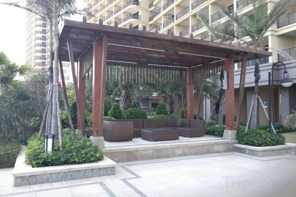Un espacio de estar al aire libre cubierto con macetas y una estructura de pérgola de madera.