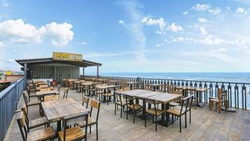 A wooden deck with tables and chairs overlooking the sea.