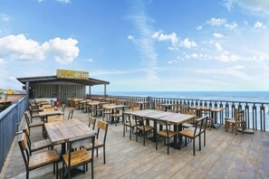 A wooden deck with tables and chairs overlooking the sea. - Huidong Shuangyue Bay Rainbow Bay Sea View Hotel (Huidong)