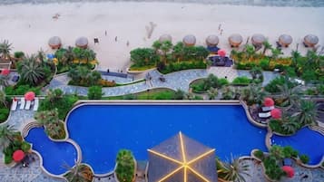 A resort with a large pool, sun loungers, and a beach area.