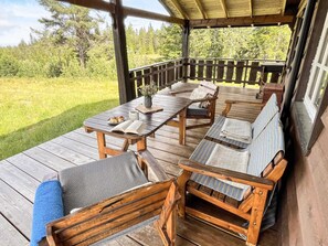 A covered outdoor deck with wooden furniture, including a table and chairs, and a bench with a towel. - 4 Star Holiday Home in Gol (Gol)