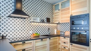 A modern kitchen with patterned backsplash, wooden cabinetry, a built-in oven, and a breakfast sign. - 4 Guests Apartment in Medulin (Liznjan)