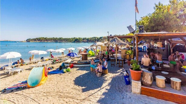 A beach with umbrellas, lounge chairs, and a bar area. - 4 Guests Apartment in Medulin (Liznjan)