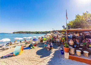 A beach with umbrellas, lounge chairs, and a bar area. - 4 Guests Apartment in Medulin (Liznjan)