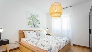 A bedroom with a bed, bedside table, lamp, and a hanging light fixture. - 4 Guests Apartment in Medulin (Liznjan)