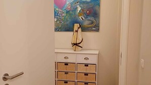 A hallway with a white door, a white cabinet with wicker baskets, and a painting of a whimsical scene with balloons and a whale. - Large vacation apartment in Nuremberg with good connections: Center, trade fair, Playmobil (Nürnberg)
