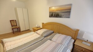 Une chambre à coucher avec un lit double, une table de chevet, une chaise, une armoire et un tableau au mur.