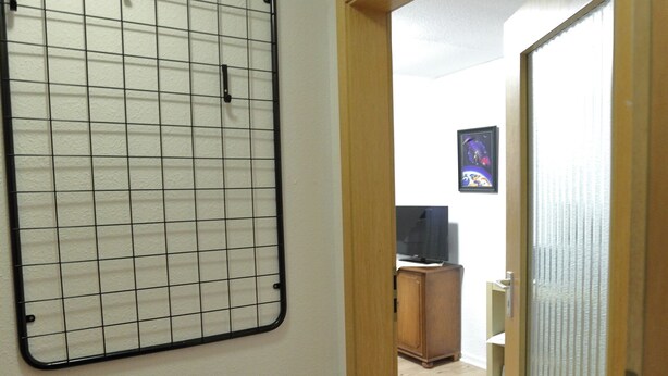 Un couloir avec un panneau mural à motifs géométriques, une porte en bois et un plancher en bois.
