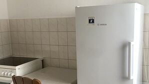 Une cuisine avec un réfrigérateur Bosch blanc, une chaise en bois et une cuisinière.