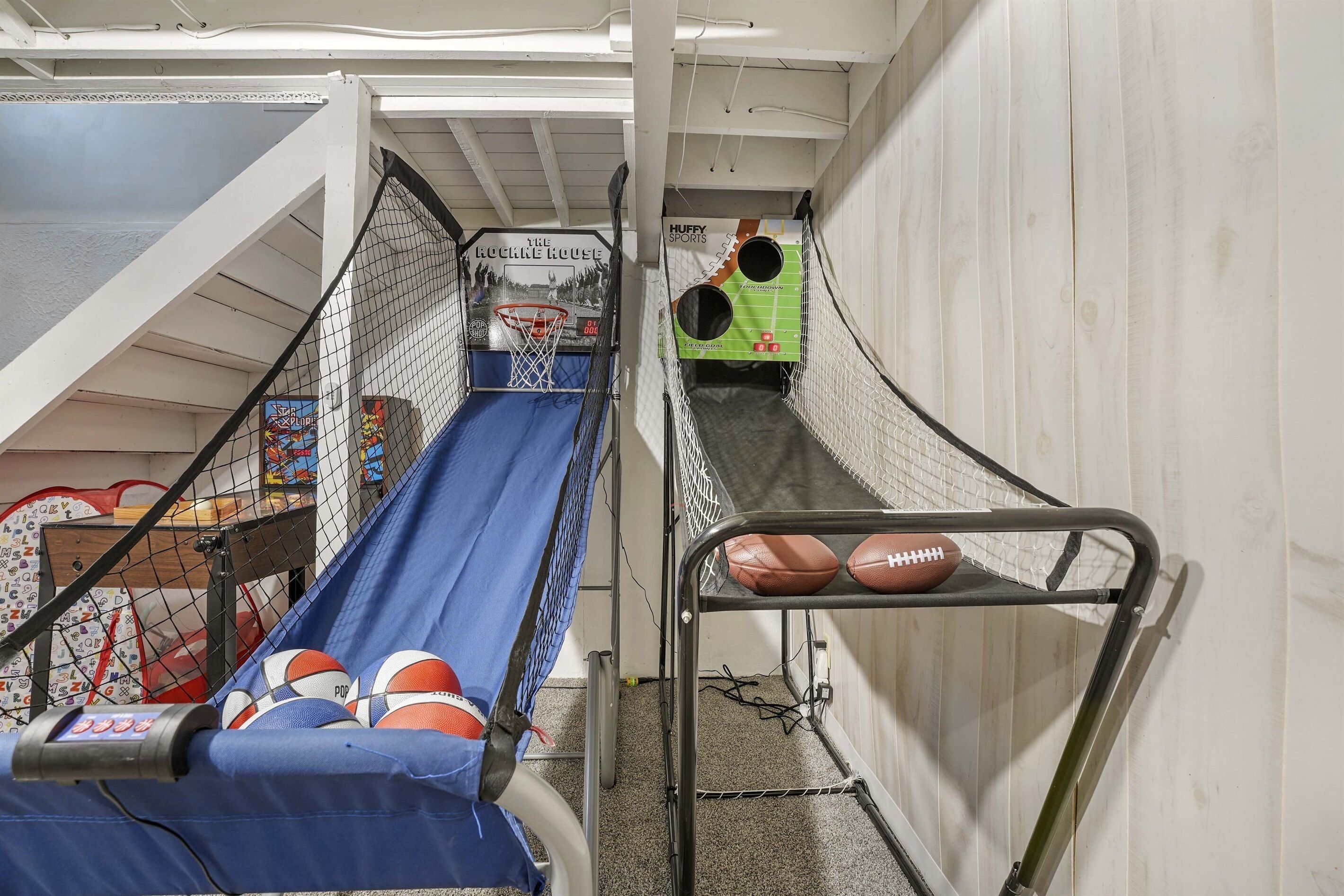 A multi-level indoor play area with basketball and football hoops, a slide, and various sports equipment.